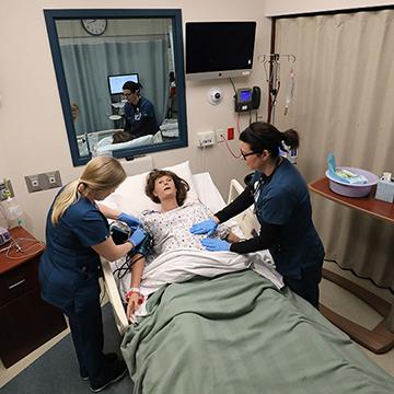 2名护生在模拟假人上练习护理，由一名护理教员观察